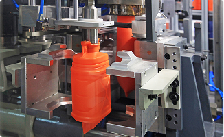 Industrial machinery using custom automation to mold an orange plastic container for consumer products.
