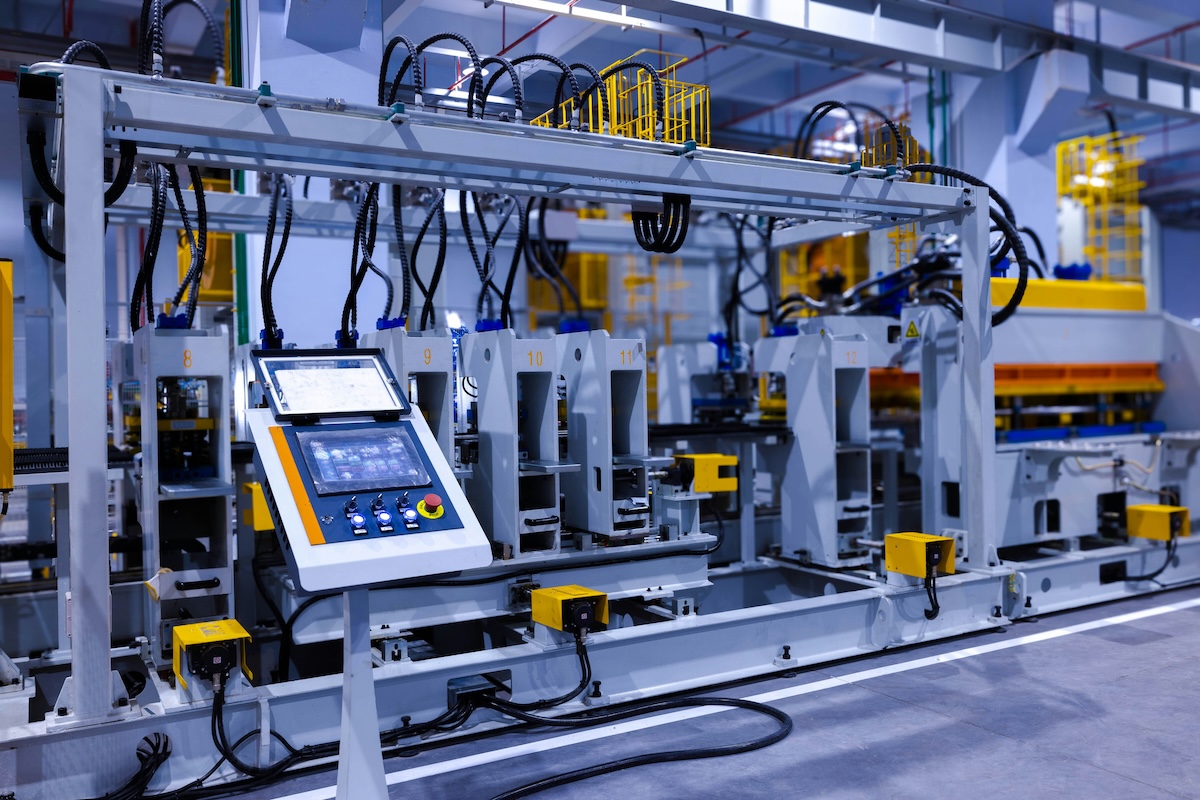 Automated industrial manufacturing machinery with a central touch screen control panel displaying modular components.